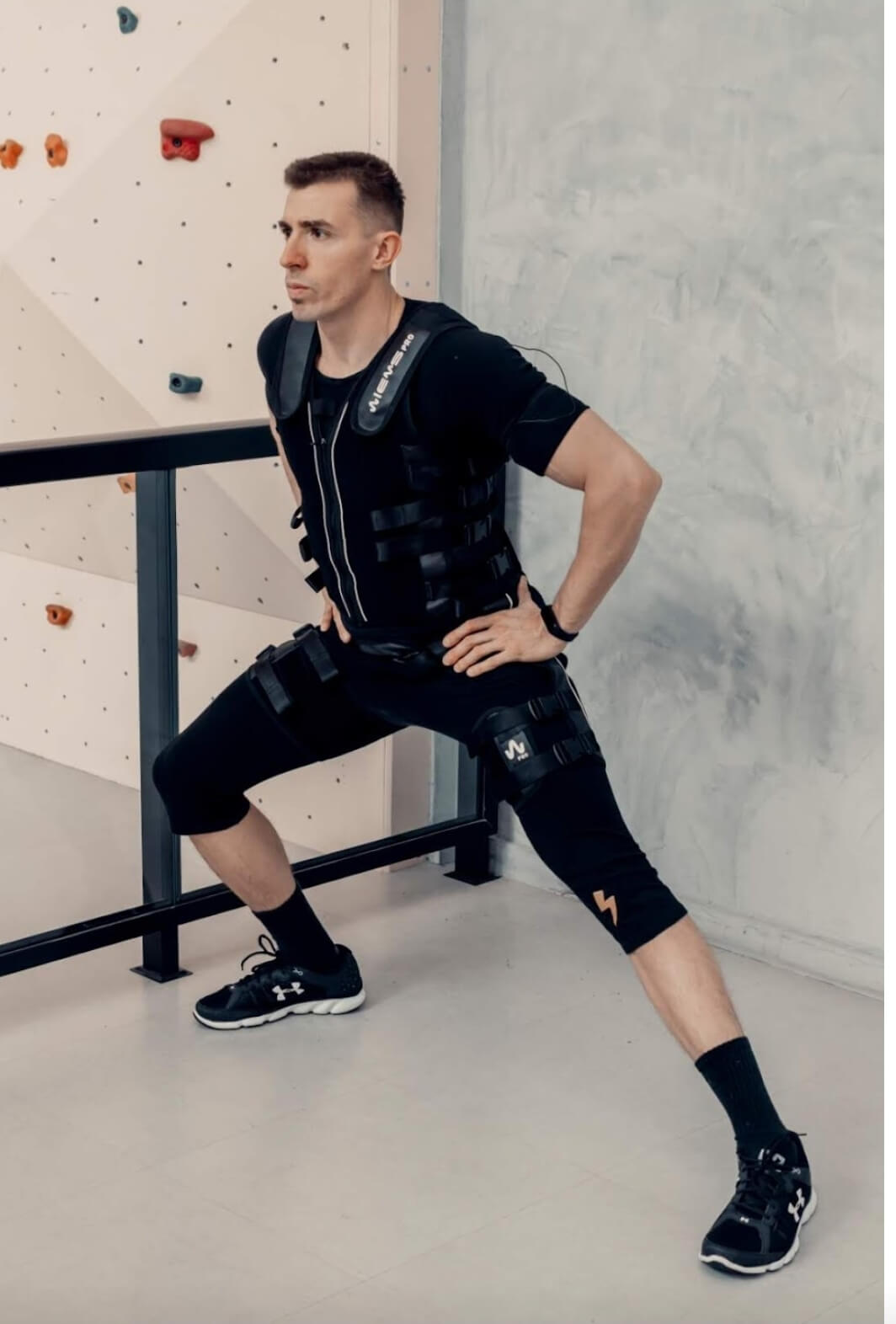 Henrique Dealtry demonstrando exercício com equipamento completo de eletroestimulação EMS em ambiente profissional